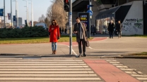 Two adults crossing a street in Zagreb, captured during daylight on a clear day.